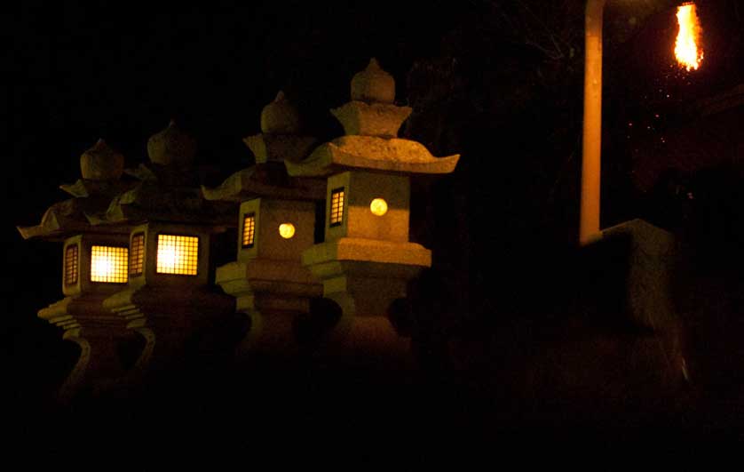 Stone lanterns illuminated by the flames.