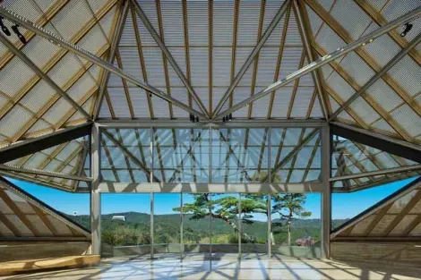 Le bâtiment du musée Miho et la large baie vitrée donnent sur un paysage de pins et d'érables