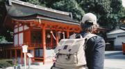 Homme avec son sac à dos devant un temple japonais