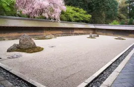 A stone garden with raked gravel and wall around the edge