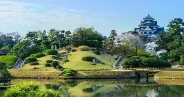 Japanese garden with large pond in the foreground and castle in the background