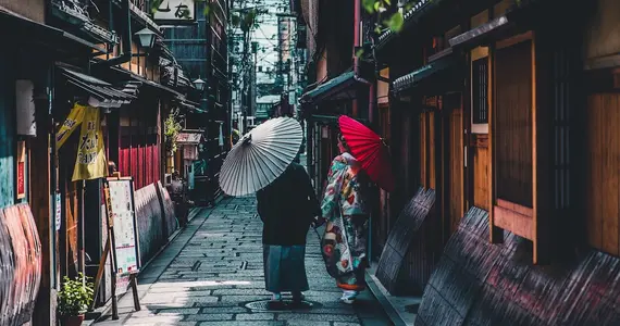 Couple walking on street while holding umbrella in Kyoto